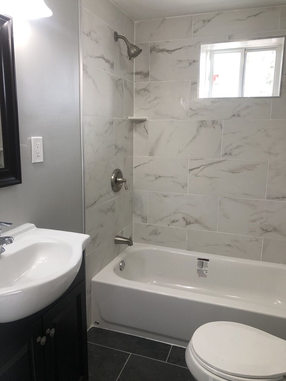 Modern bathroom with white-and-gray marble-look tile and a dark wood vanity