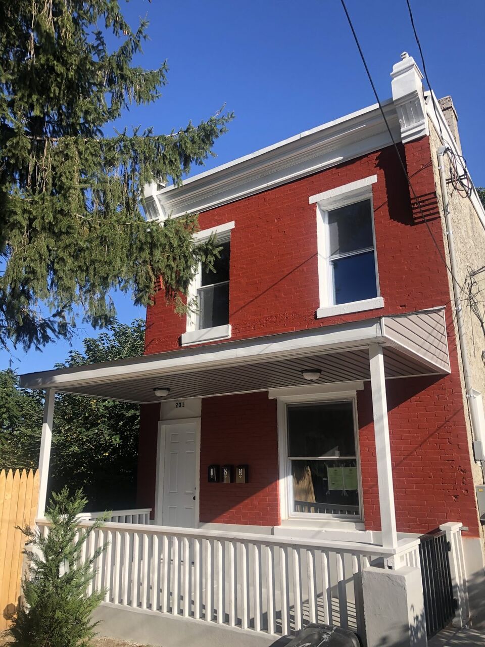 Freshly painted red-brick home with a white covered porch